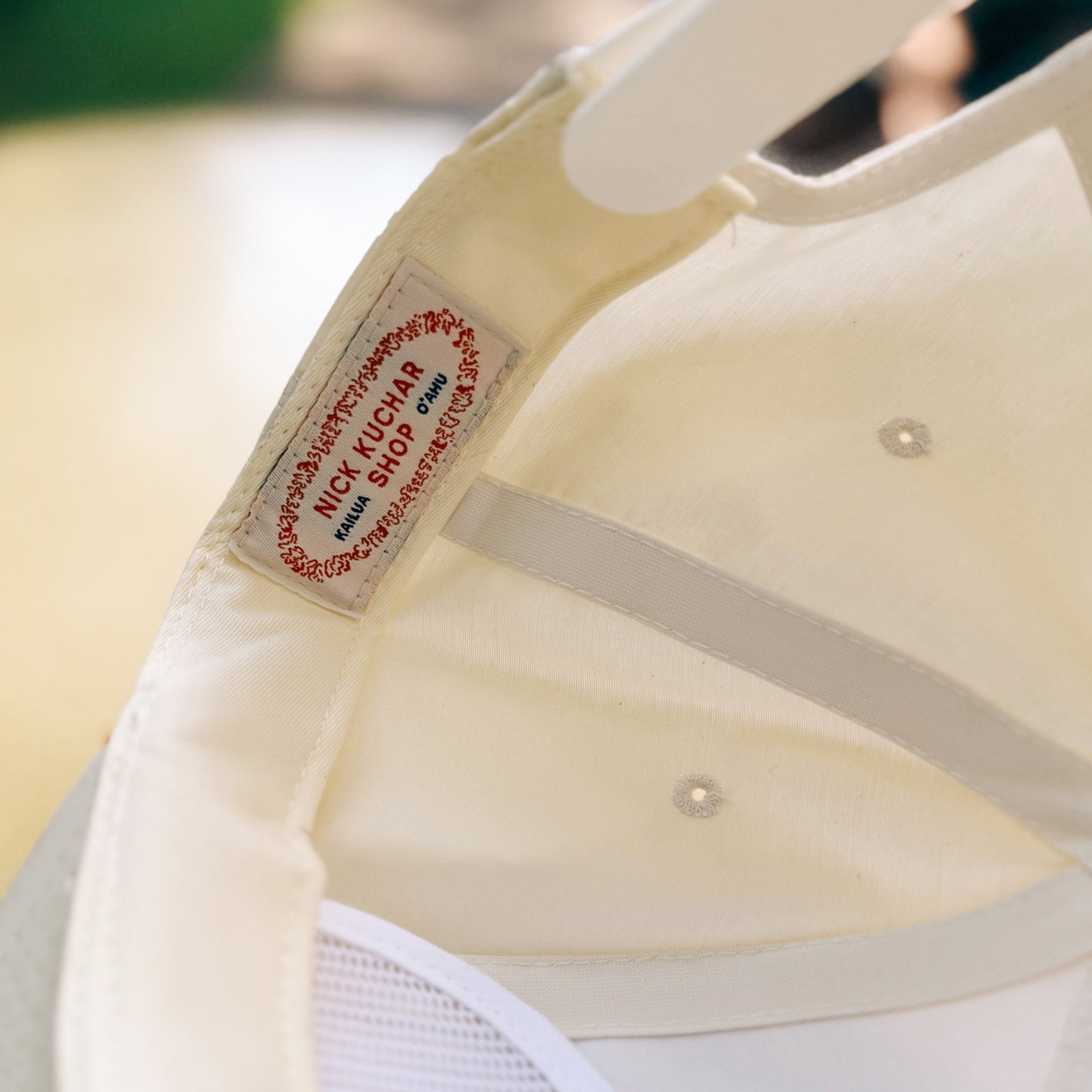 Close-up of a beige cap with a nick kuchar brand label on a blurred background