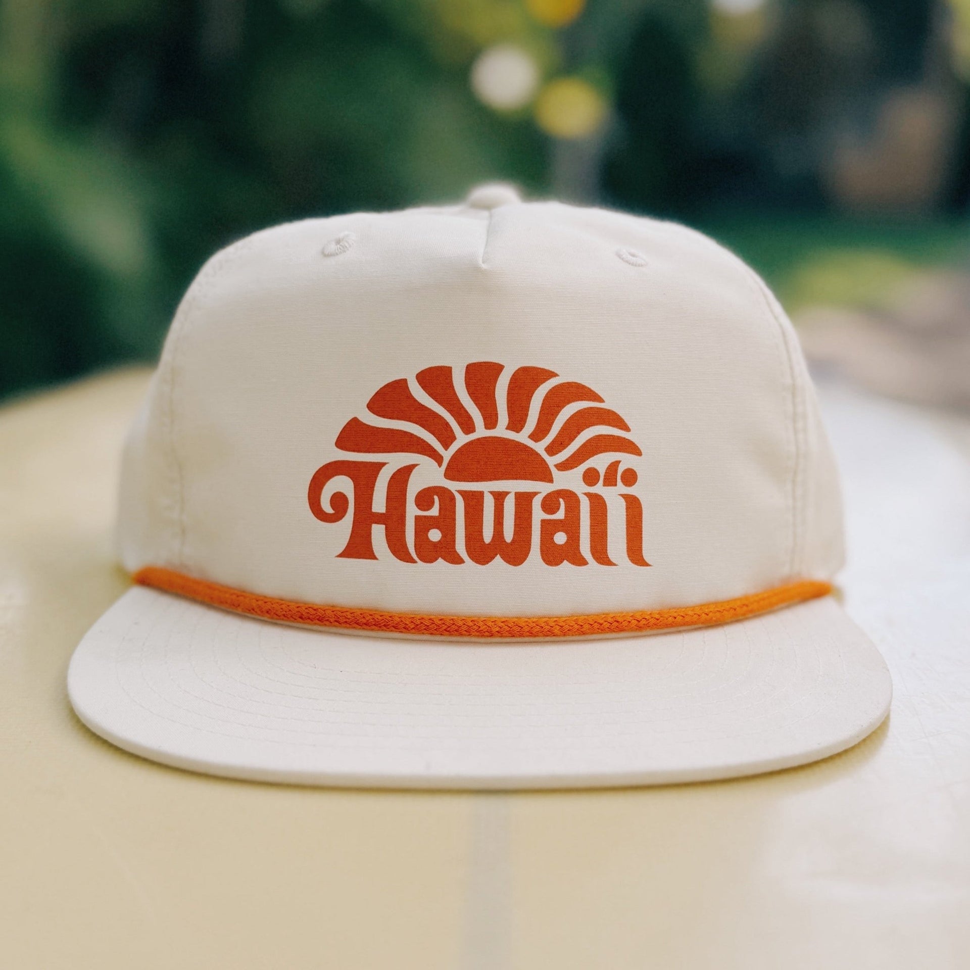 Beige cap with 'Hawaii' logo on a blurred natural background