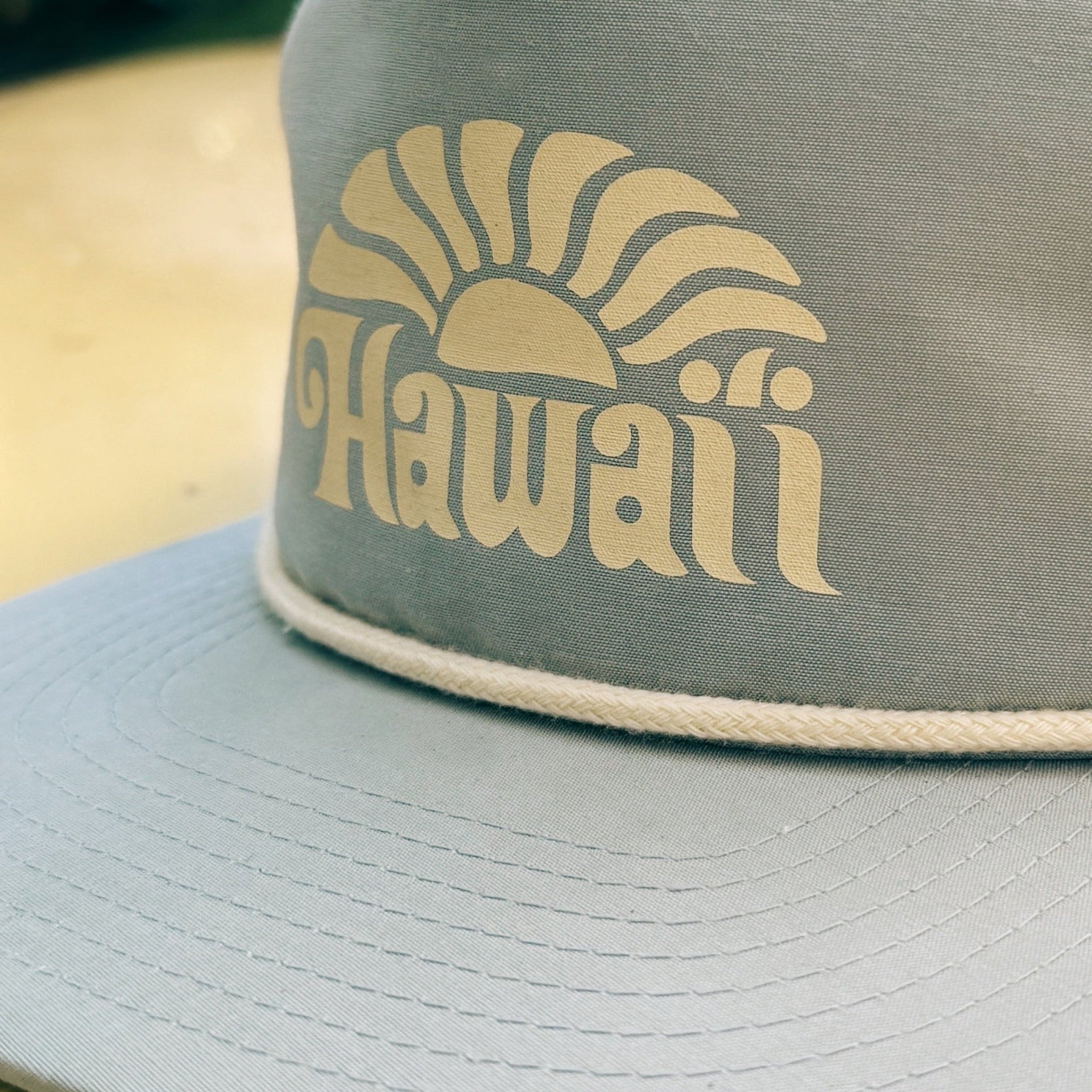 Gray cap with 'Hawaii' and sun graphic on a wooden surface