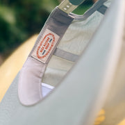 Light gray cap with a nick kuchar brand label on a blurred green and yellow background