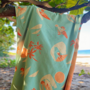 Beach towel with tropical pattern hanging on a tree branch by the beach