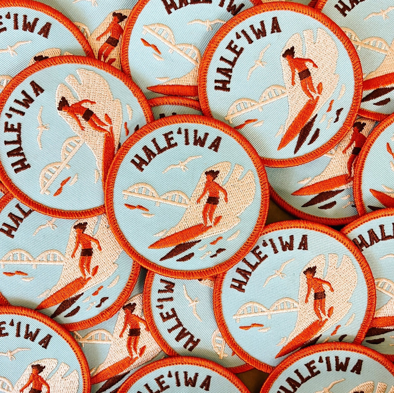 Embroidered 2.75" patch featuring a surfer, Anahulu Stream Bridge, and ‘Iwa bird. Vibrant design with an iron-on backing.