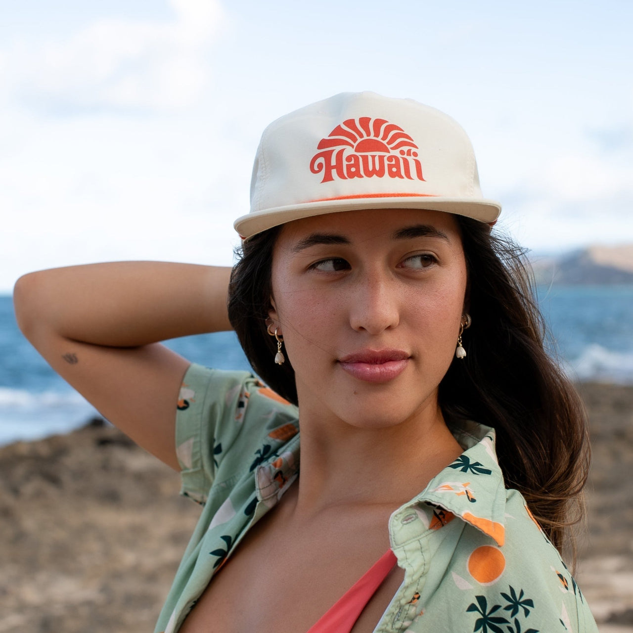Woman wearing a cap with 'Hawaii' text on a beach