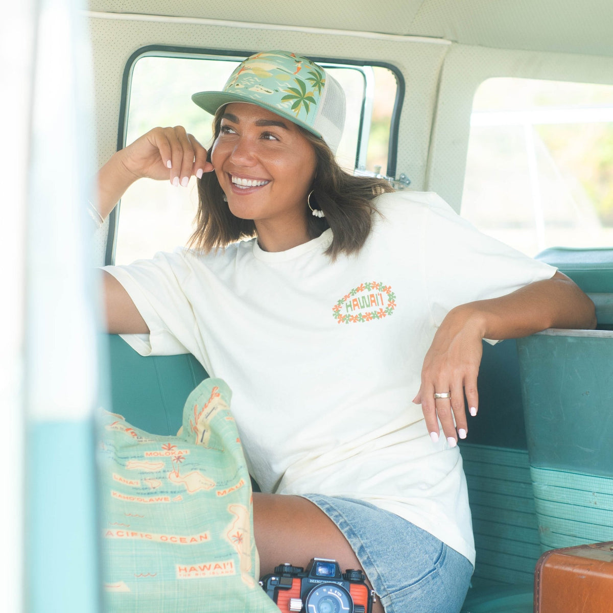 woman wearing hawaii beach trucker hat inside vintage van