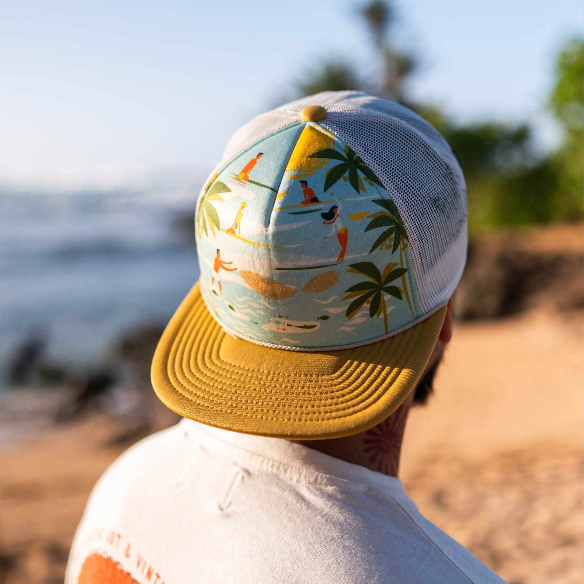 Person wearing a colorful cap and white shirt on a beach