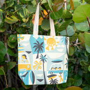 Tote bag with beach-themed design hanging among green leaves