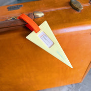 Vintage suitcase with a yellow tag and red handle on a wooden surface