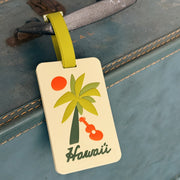 Luggage tag with palm tree and ukulele design on a suitcase.