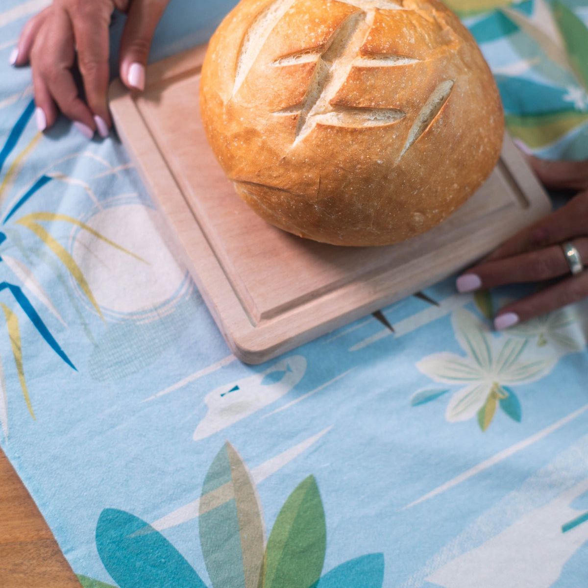 setting a loaf of sourdough on top of a kitchen tea towel with surf artwork on it