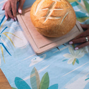 setting a loaf of sourdough on top of a kitchen tea towel with surf artwork on it