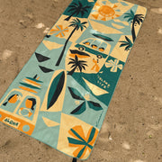 Colorful towel with island life design on a sandy surface