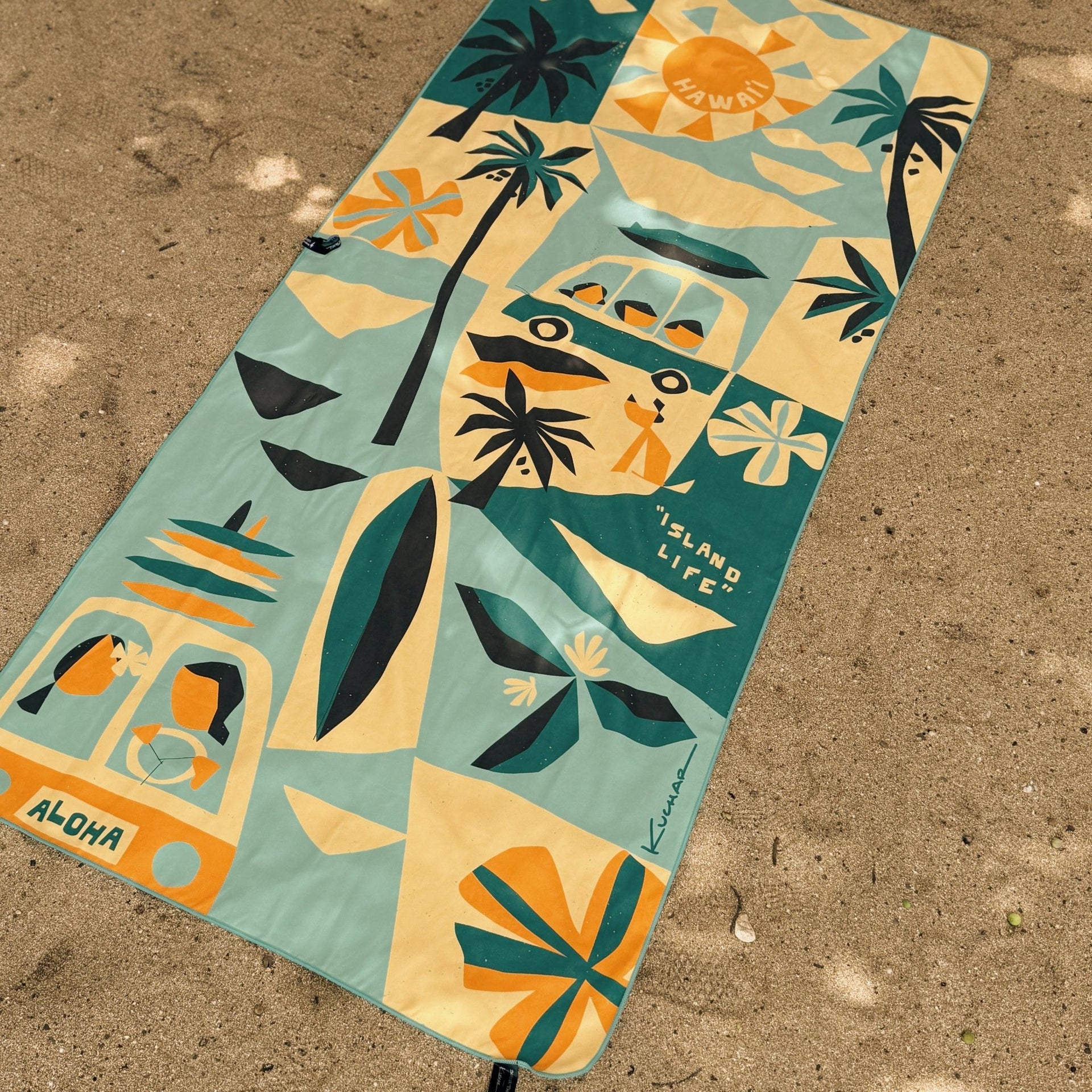 Colorful towel with island life design on a sandy surface