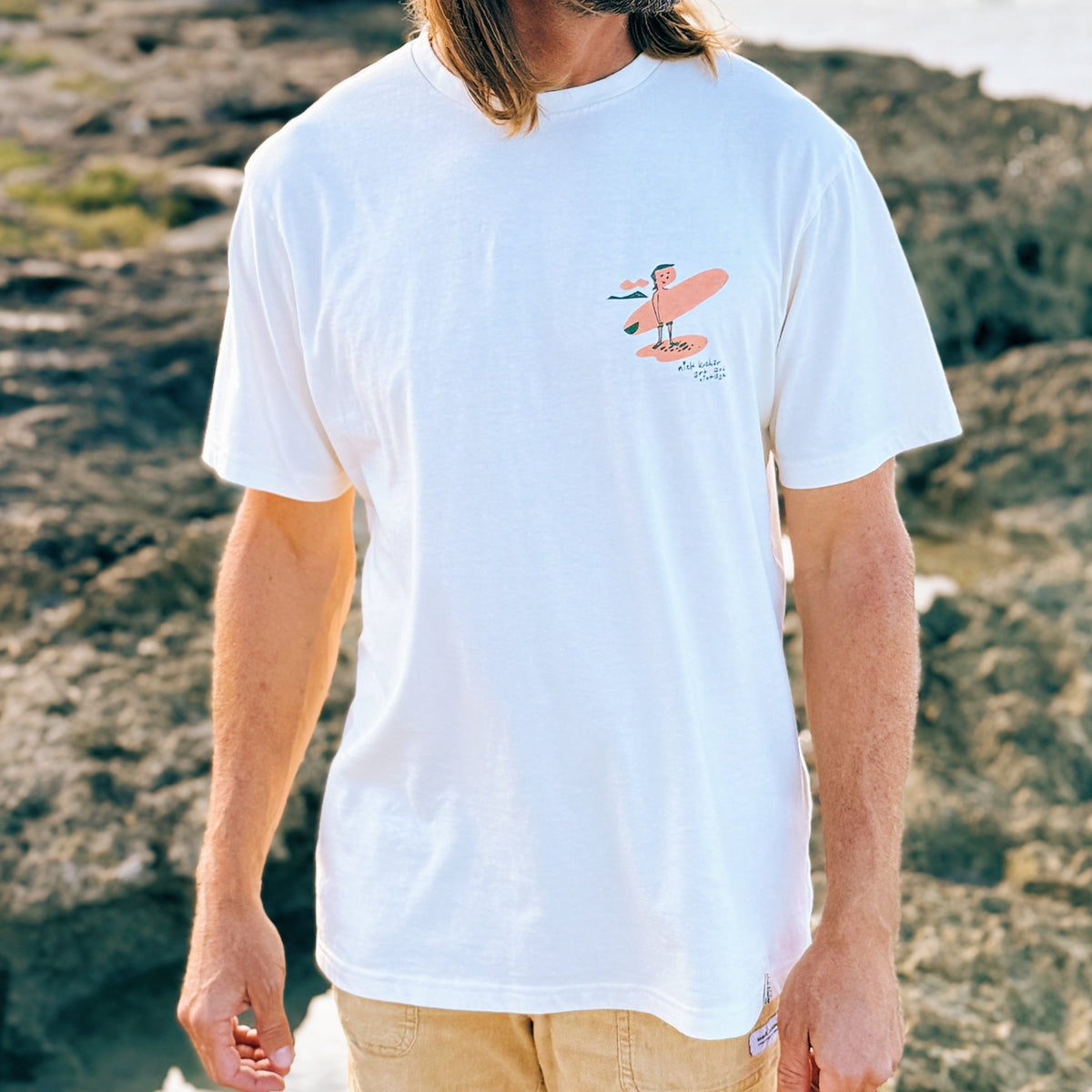 Man wearing a white Hawaii surf t-shirt with a graphic design outdoors