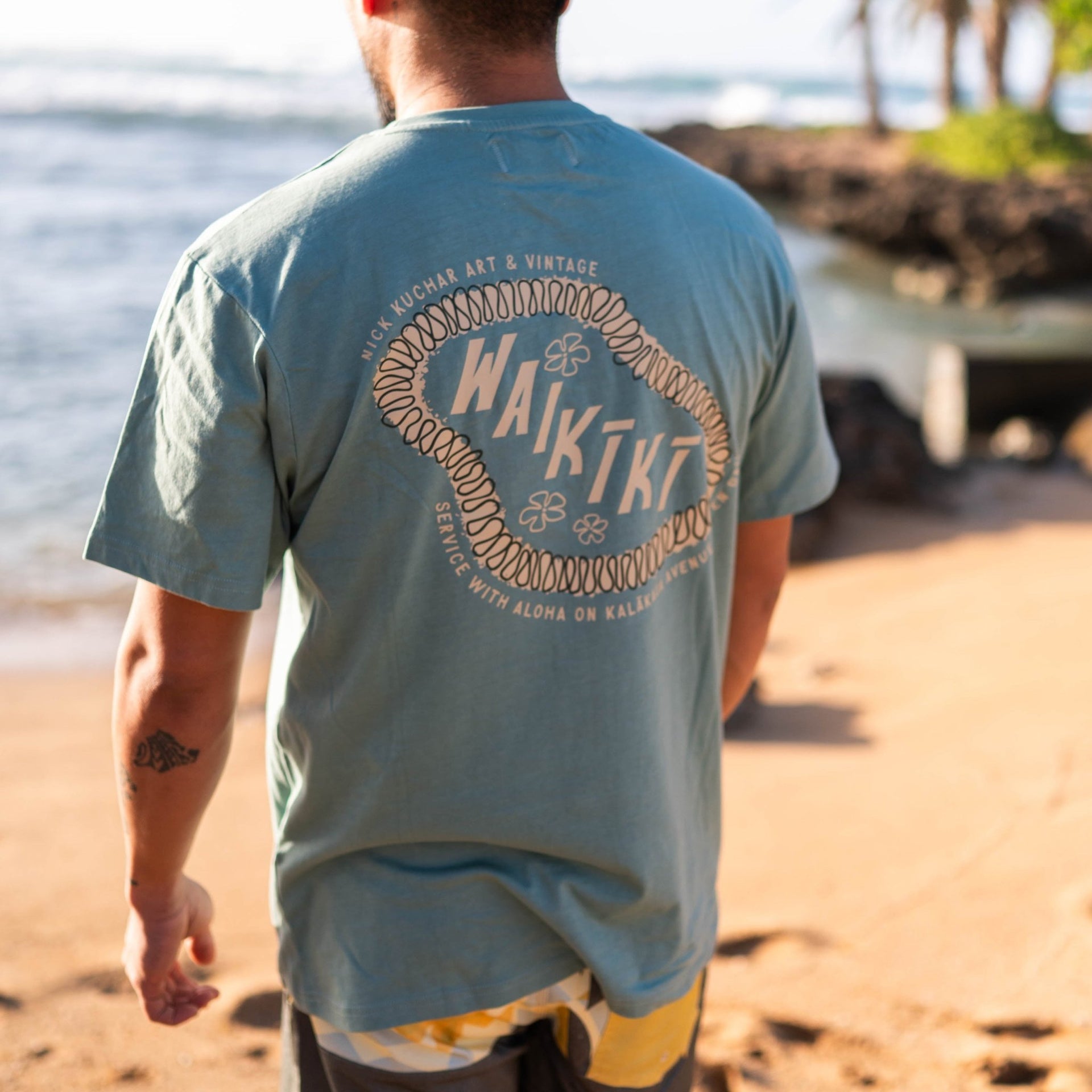 wearing a blue tee shirt that says waikiki at the beach